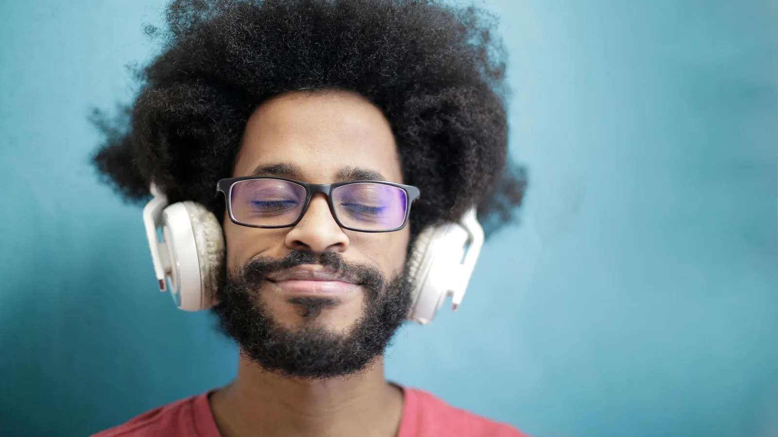 目を閉じてヘッドホンで音を聞く男性
