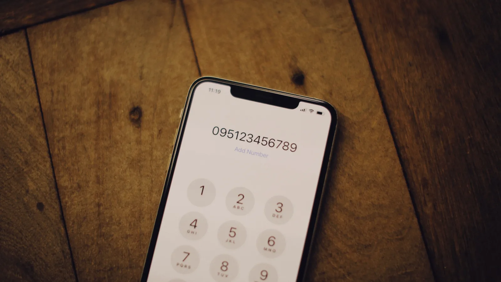 木のテーブルに置かれたスマートフォンの数字入力画面